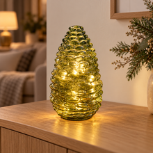 Evergreen glass pinecone LED light illuminated on an oak sideboard in a cosy living room
