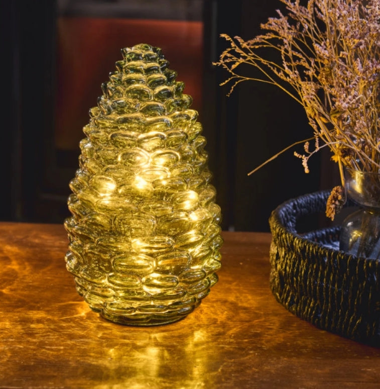 Evergreen green glass pinecone light with 15 warm white LEDs, shown illuminated on a table